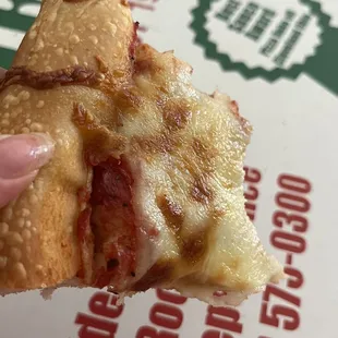 a hand holding a piece of pizza