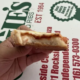 a hand holding a half eaten pizza