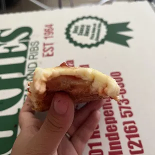 a hand holding a half eaten pizza