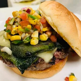 a burger with corn, peppers, and cheese