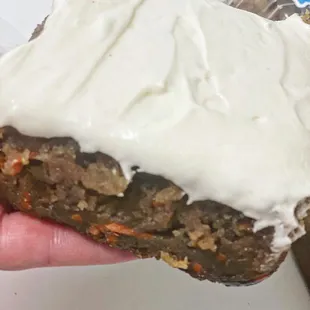 a hand holding a piece of carrot cake