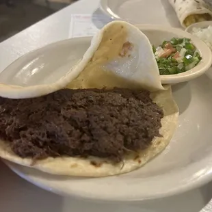 Barbacoa taco on flour tortilla.