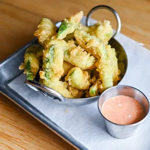 a tray of fried broccoli and sauce
