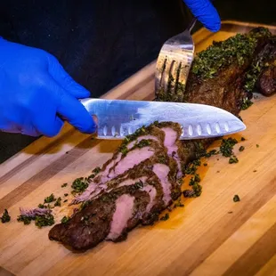 a person cutting a piece of meat on a cutting board