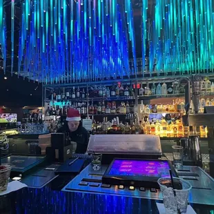a bar with blue lights and bottles of alcohol