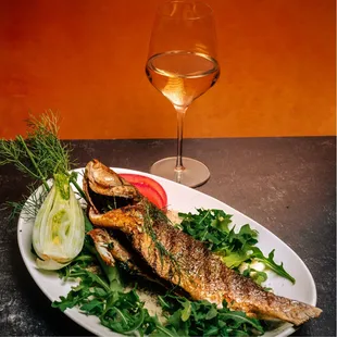 a plate of fish and a glass of wine