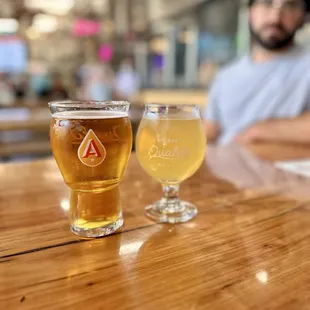 a man sitting at a table with two glasses of beer