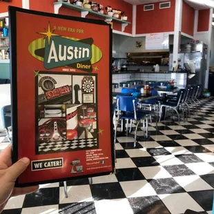 Inside the diner and holding a menu.