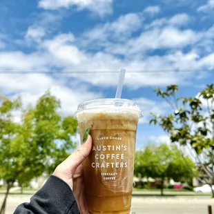 a hand holding a cup of iced coffee