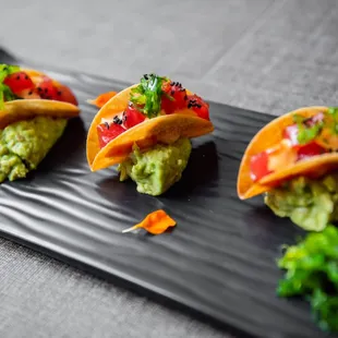 three tacos on a black plate