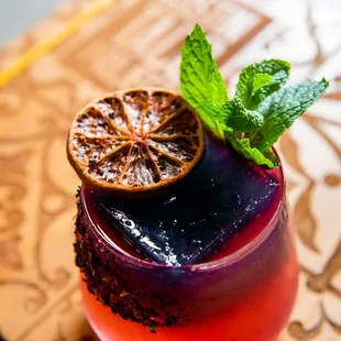 a colorful drink with a slice of orange on top