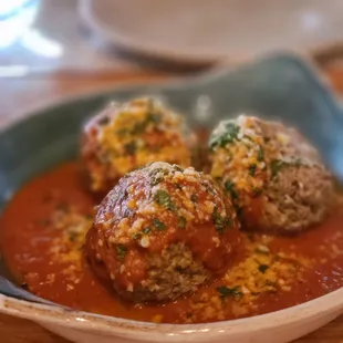three meatballs covered in sauce in a bowl