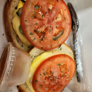 Egg, avocado,  tomato,  and jack bagel sandwich