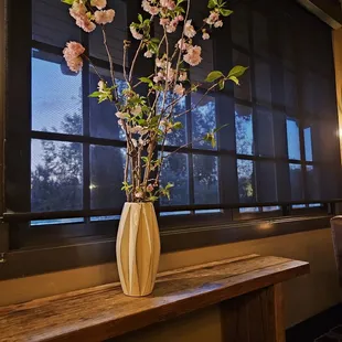 a vase of flowers on a table in front of a window