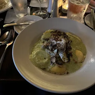 Ravioli Carciofi with an incredible house made pesto sauce topped with sautéed mushrooms and artichoke hearts.