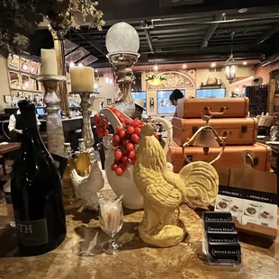 a table with a rooster and wine bottles
