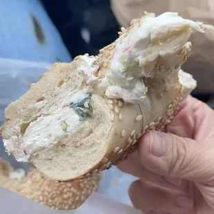 a hand holding a sandwich with a bite taken out of it