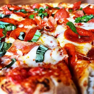  a pizza with pepperoni, basil, and mozzarella