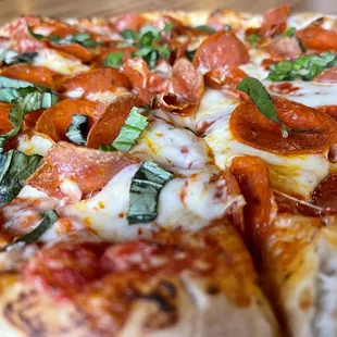  a pizza with pepperoni, basil, and mozzarella