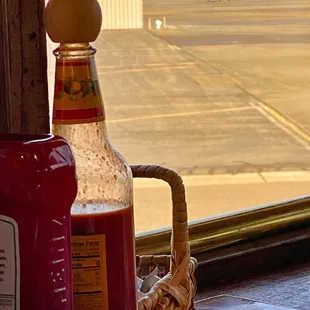 a bottle of ketchup and a baseball glove on a window sill