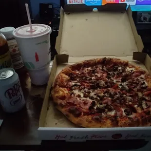 a pizza in a pizza box and a drink