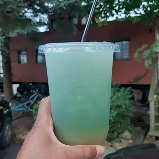 a hand holding a green drink