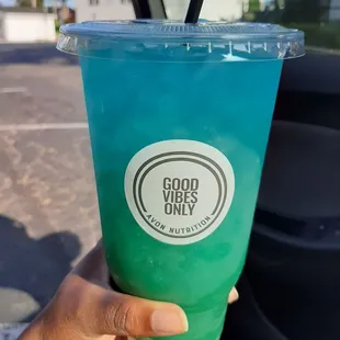 a hand holding a blue drink
