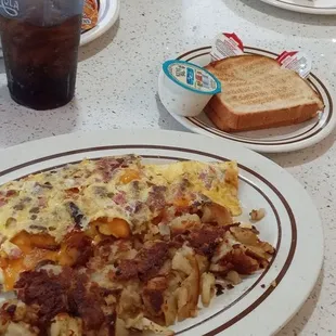 Meat omelette with home fries and toast with a side of ranch dressing.