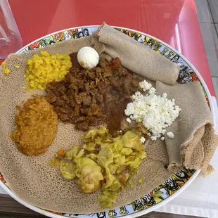 Dinner plate with injera, tibs, shiro, and veggies