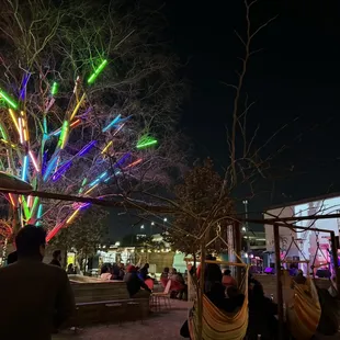 people sitting in hammocks under a colorful tree