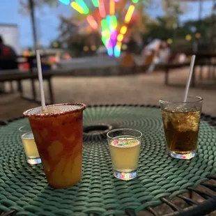 three drinks on a table in front of a colorful tree