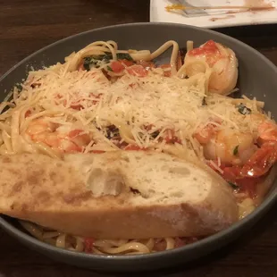 a bowl of pasta with shrimp and bread
