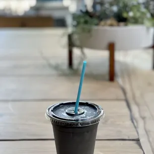 a black cup with a blue straw