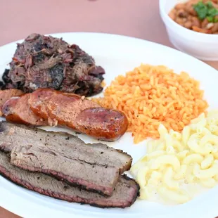 a plate of meat, macaroni, and cheese