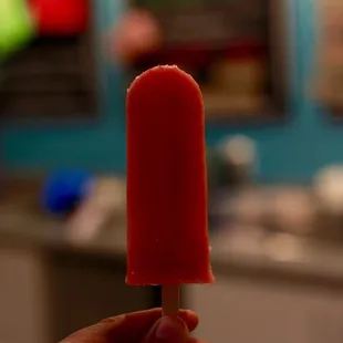 a hand holding a red popsicle