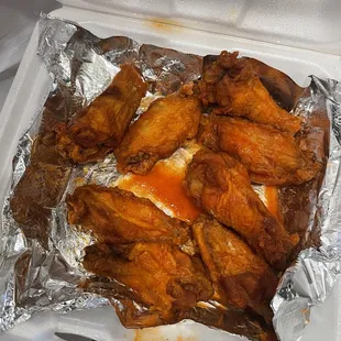 chicken wings in foil in a styrofoam container