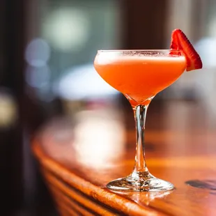 a cocktail with a strawberry garnish on the rim