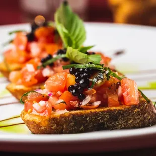 a piece of toasted bread topped with tomatoes and black olives