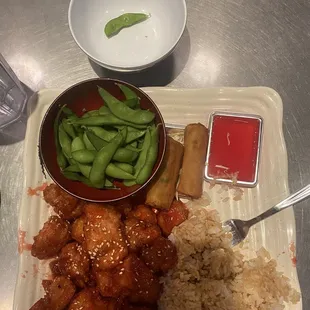 Orange chicken dinner with edamame, steamed rice, and spring rolls