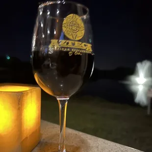 a glass of wine next to a candle