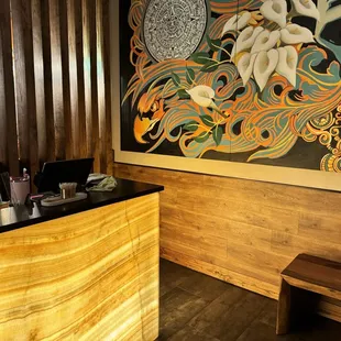 a wooden reception desk with a large mural on the wall