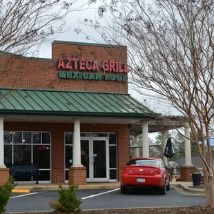 a red car parked in front of a mexican restaurant