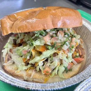 La cachetona torta, asada, al pastor and chorizo,beans,cheese, guacamole, pico, lettuce red and green sauce on a doble size telera roll