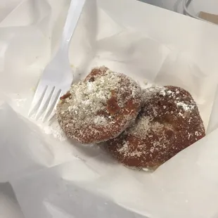 a fork in a basket of powdered sugar pastries