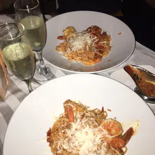two plates of pasta and a glass of wine