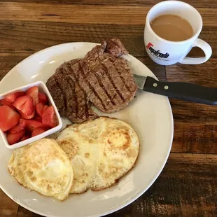 Rib eye steak with fried eggs and sliced strawberries. Great coffee too!