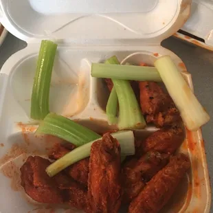 chicken wings and celery in a styrofoam container