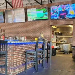 a brick bar with chairs and televisions