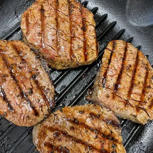 three steaks cooking in a skillet