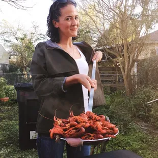 a woman holding a tray of craws